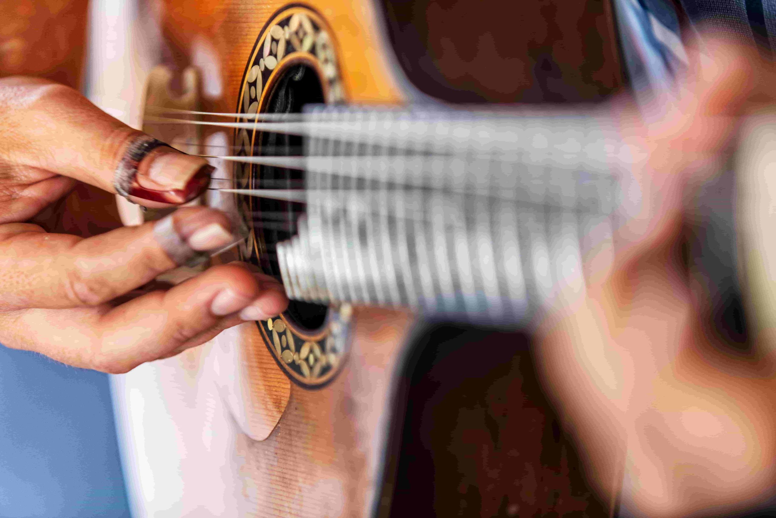 Mãos a tocar guitarra portuguesa, em plano aproximado
