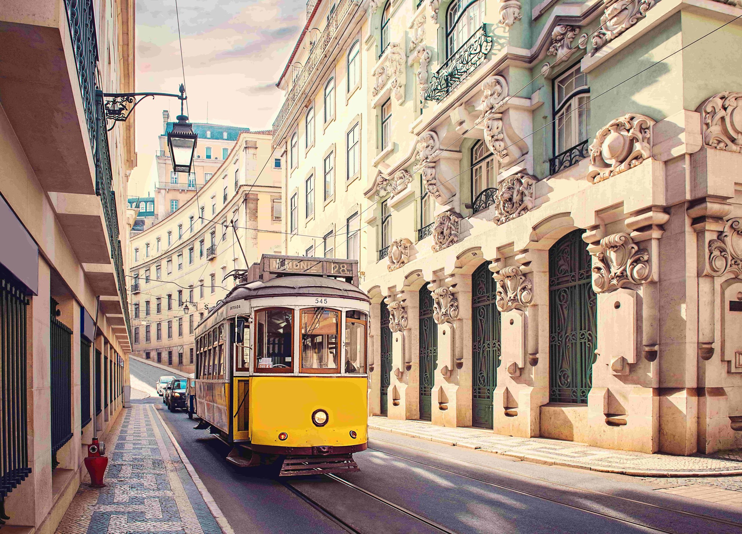 Elétrico amarelo tradicional a circular numa rua histórica de Lisboa
