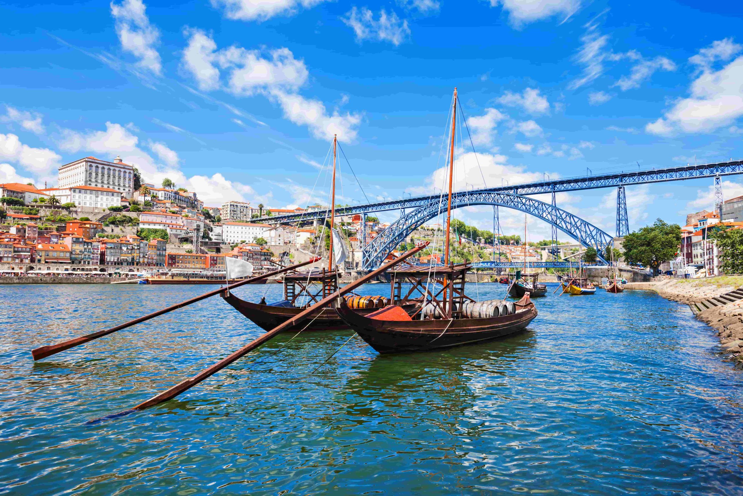Barcos rabelos no rio Douro, com a Ponte D. Luís I e a cidade do Porto ao fundo