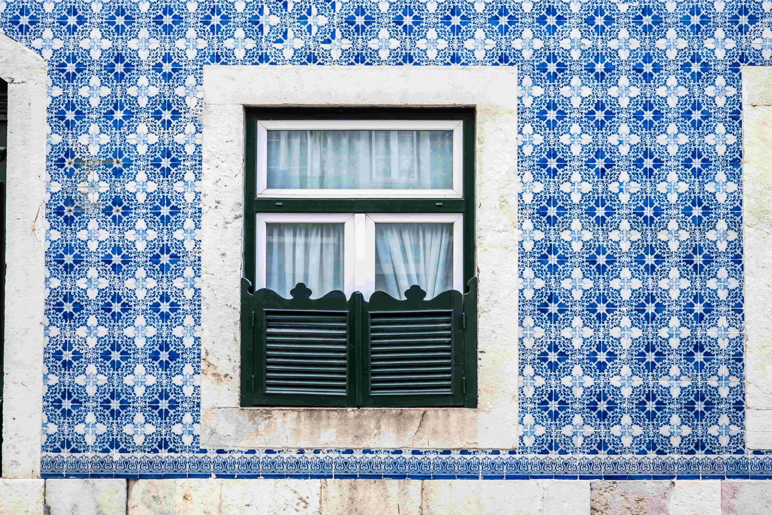 Fachada revestida a azulejos azuis tradicionais, com janela de portadas verdes