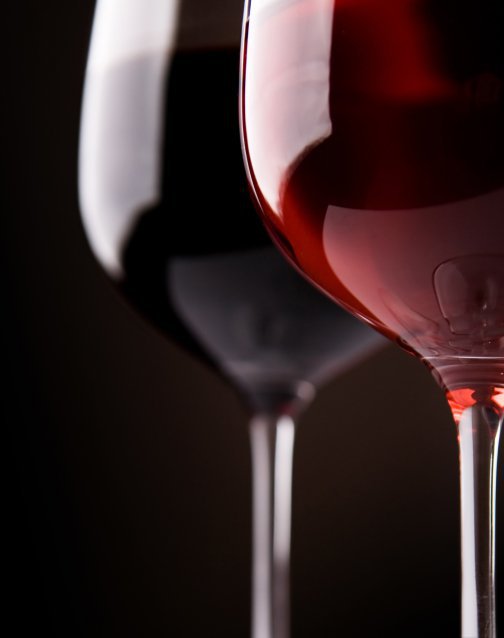 Dois copos de vinho tinto sobre fundo escuro