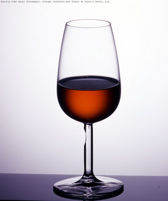Copo de Vinho do Porto de tonalidade acastanhada, sobre fundo cinzento