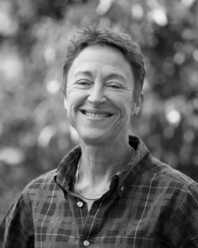 Fotografia a preto e branco de Julia Harding, Master of Wine, sorrindo ao ar livre vestindo uma camisa axadrezada